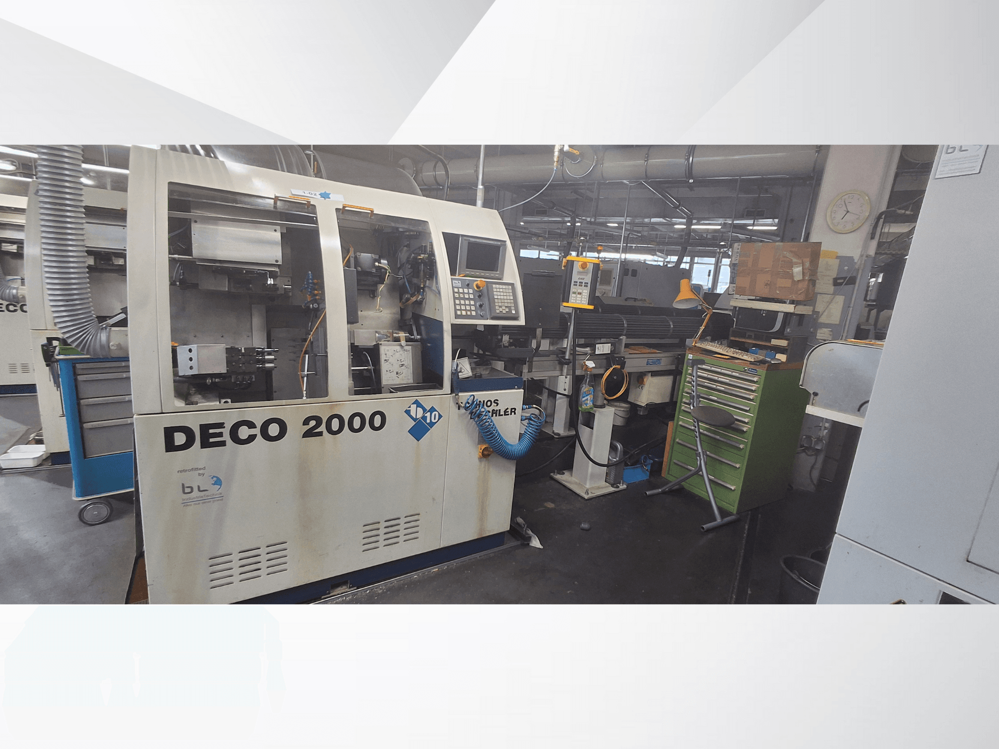 DECO 2000 machine viewed from the front, featuring control panel, pipes, and a cluttered workspace with tools and boxes.