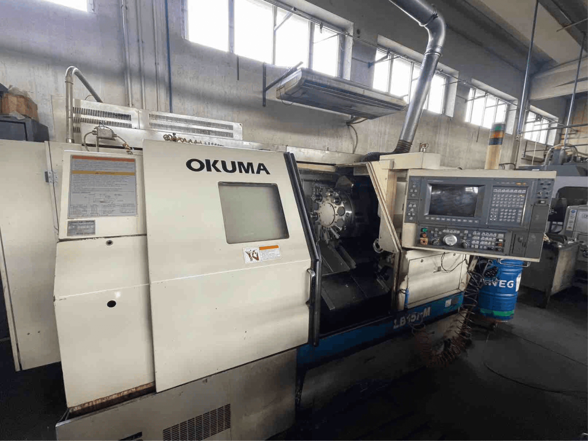 Okuma LB15i-M horizontal turning machine, front view; features control panel and cutting tool area with detailed indicators.