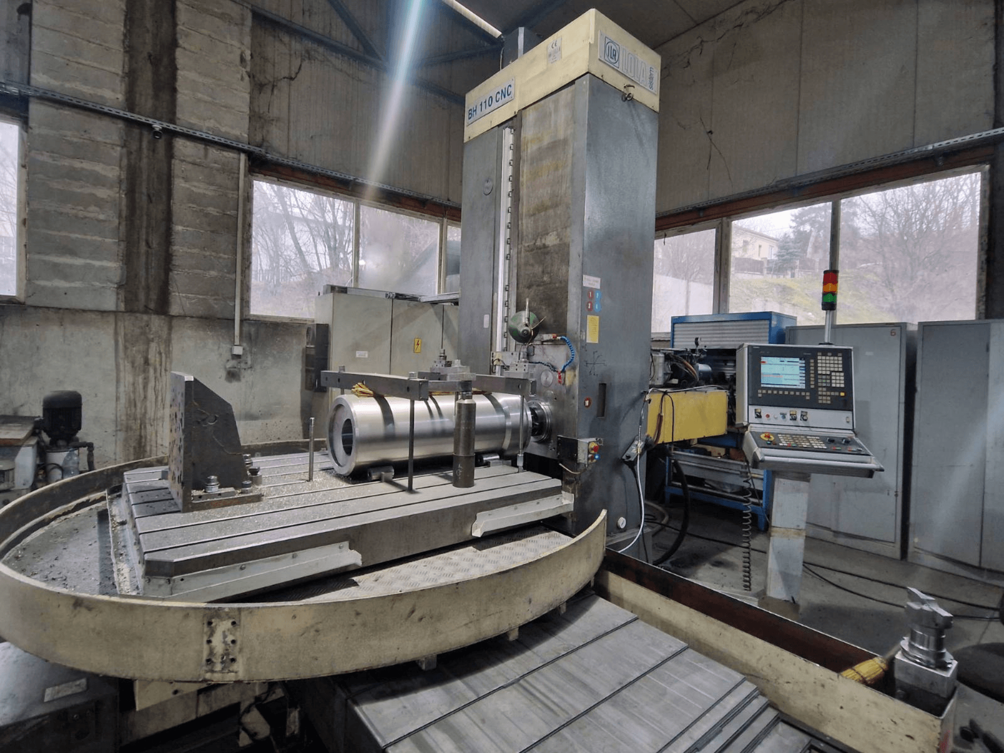 LOLA BH 110 CNC boring machine in a workshop, front view, featuring metal workpiece and control panel.
