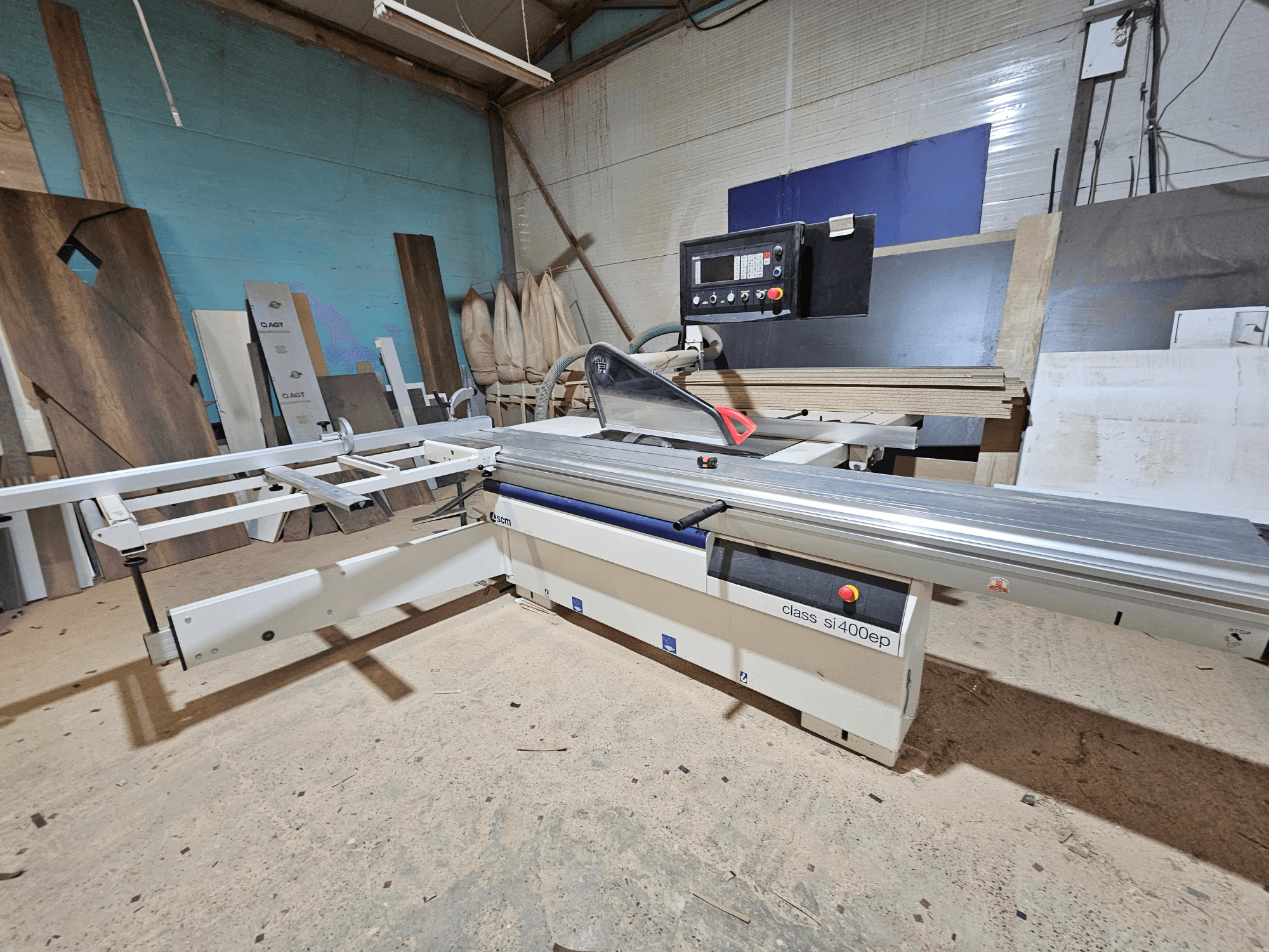 Class SI400EP panel saw, front view, with adjustable fence, set on sandy workshop floor, surrounded by wood panels.
