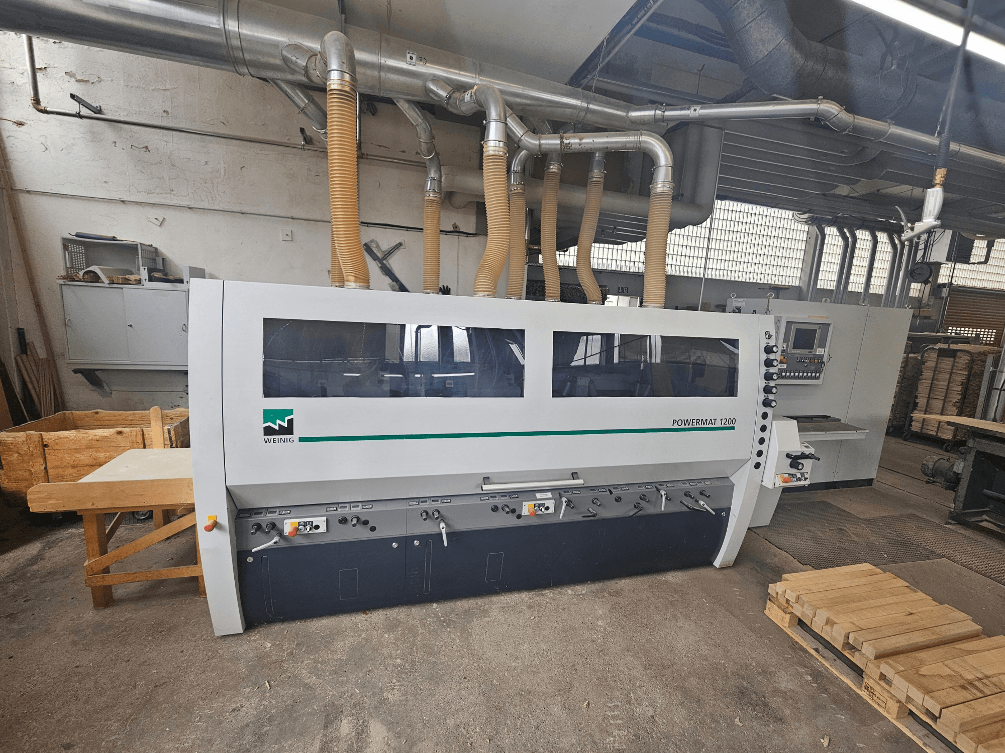 Weinig Powermat 1200 woodworking machine, front view, with control panel and wood stacks in a workshop setting.