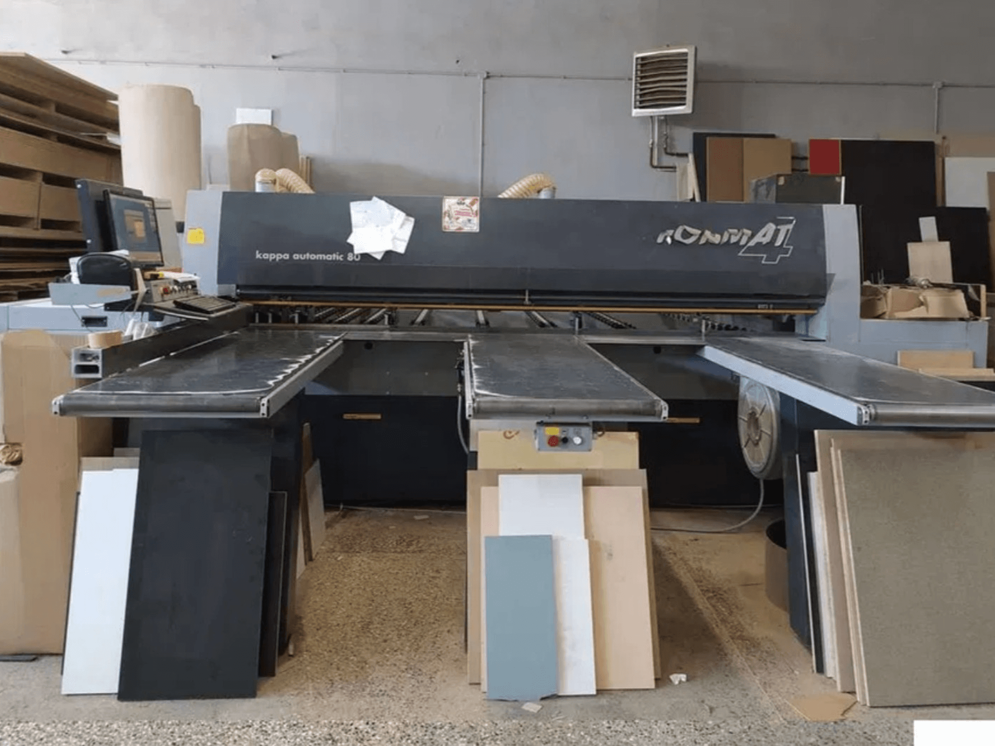 Kappa Automatic 80 model shown from the front with conveyor belts; various boards nearby in a workshop setting.