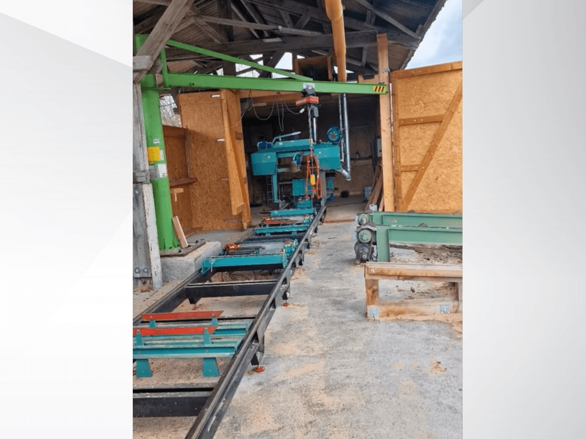 Horizontal band saw machine in workshop, viewed from the front. Equipment includes a track and additional green accessories.