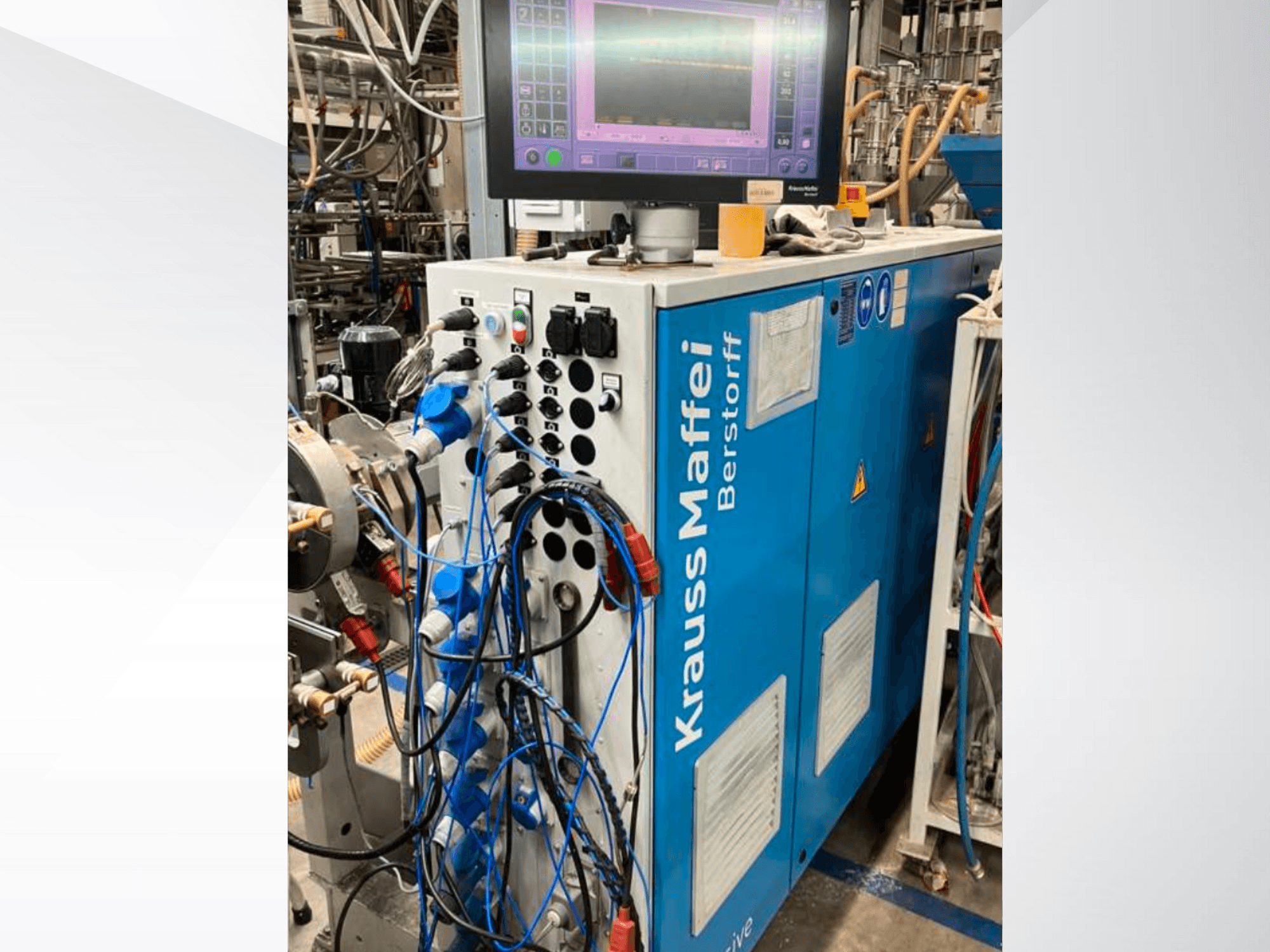 Krauss Maffei Berstorff industrial machine with control panel and monitor, featuring various buttons and connected hoses, side view.