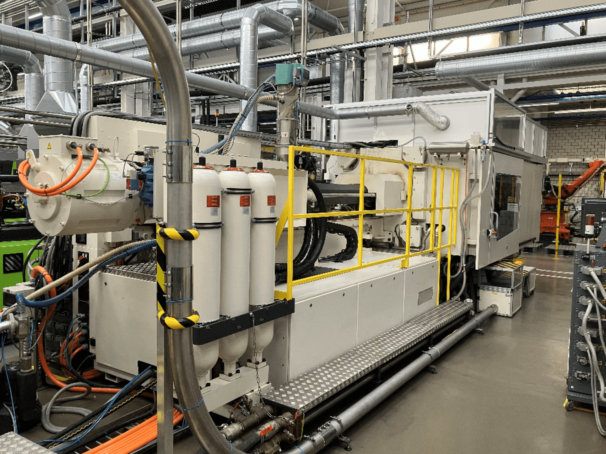 Industrial machine with white and gray casing, multiple hoses, and filter tanks; side view showcasing operational setup.
