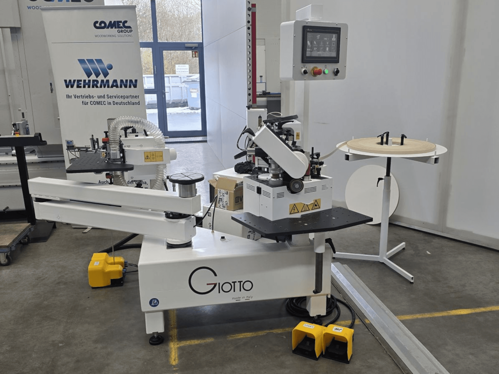 Giotto wood processing machine with control panel, side view, includes foot pedals and rotating work surface.