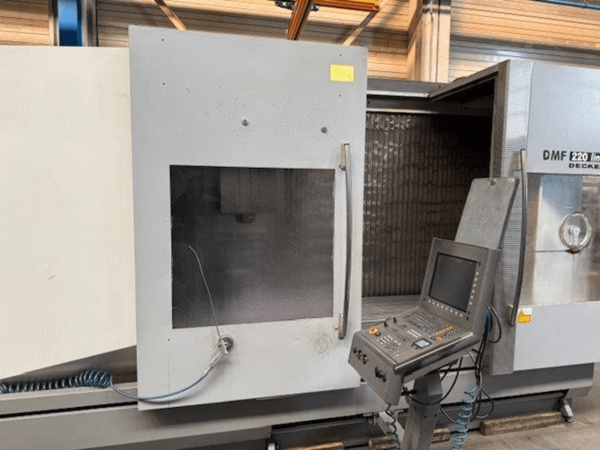 Front view of DECKEL MAHO DMF 220 Linear vertical machining center, showcasing the control panel and open machine door.