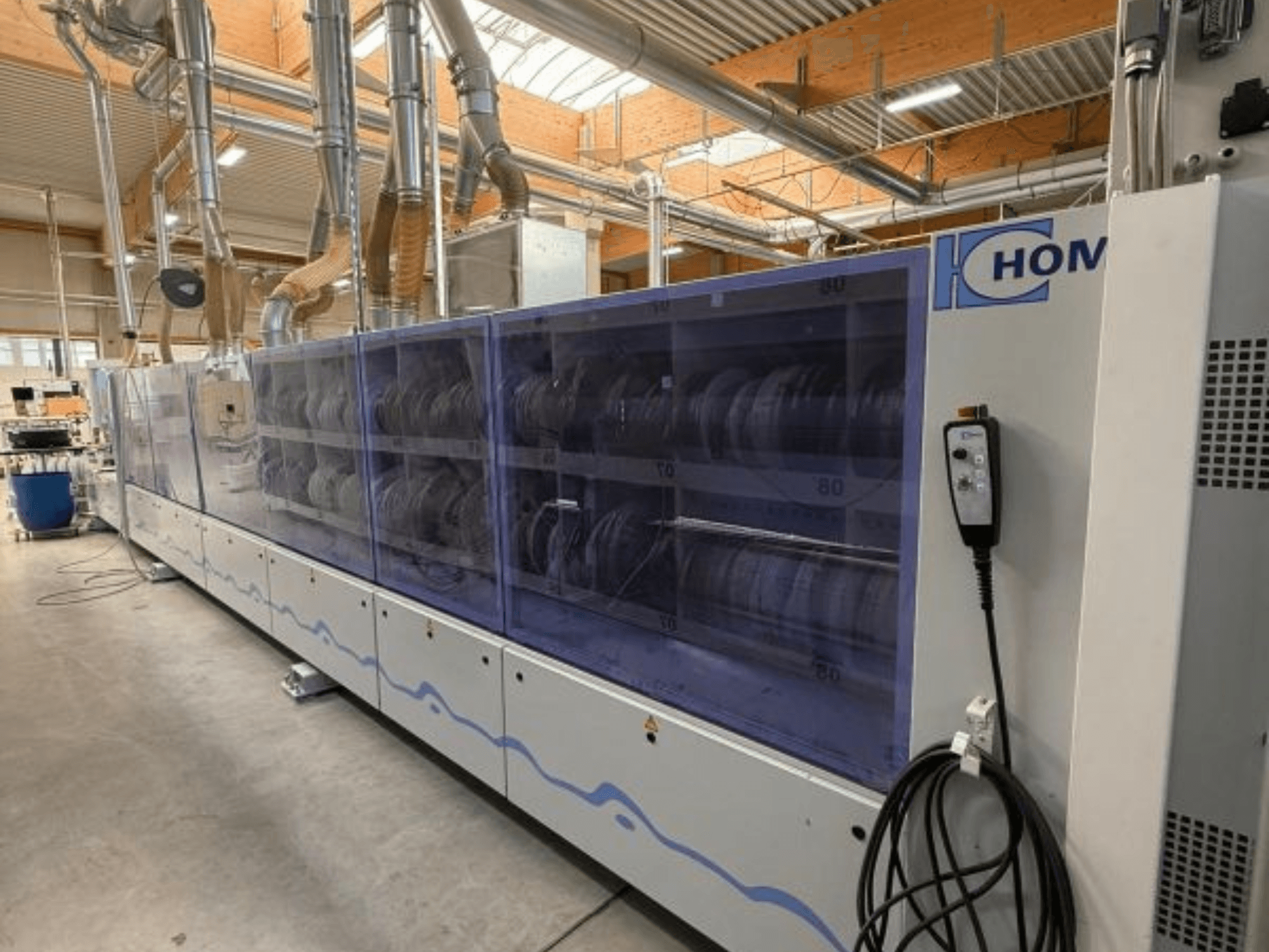 HOM industrial washing machine, front view, featuring transparent panel displaying dishes; control panel with buttons on the side.