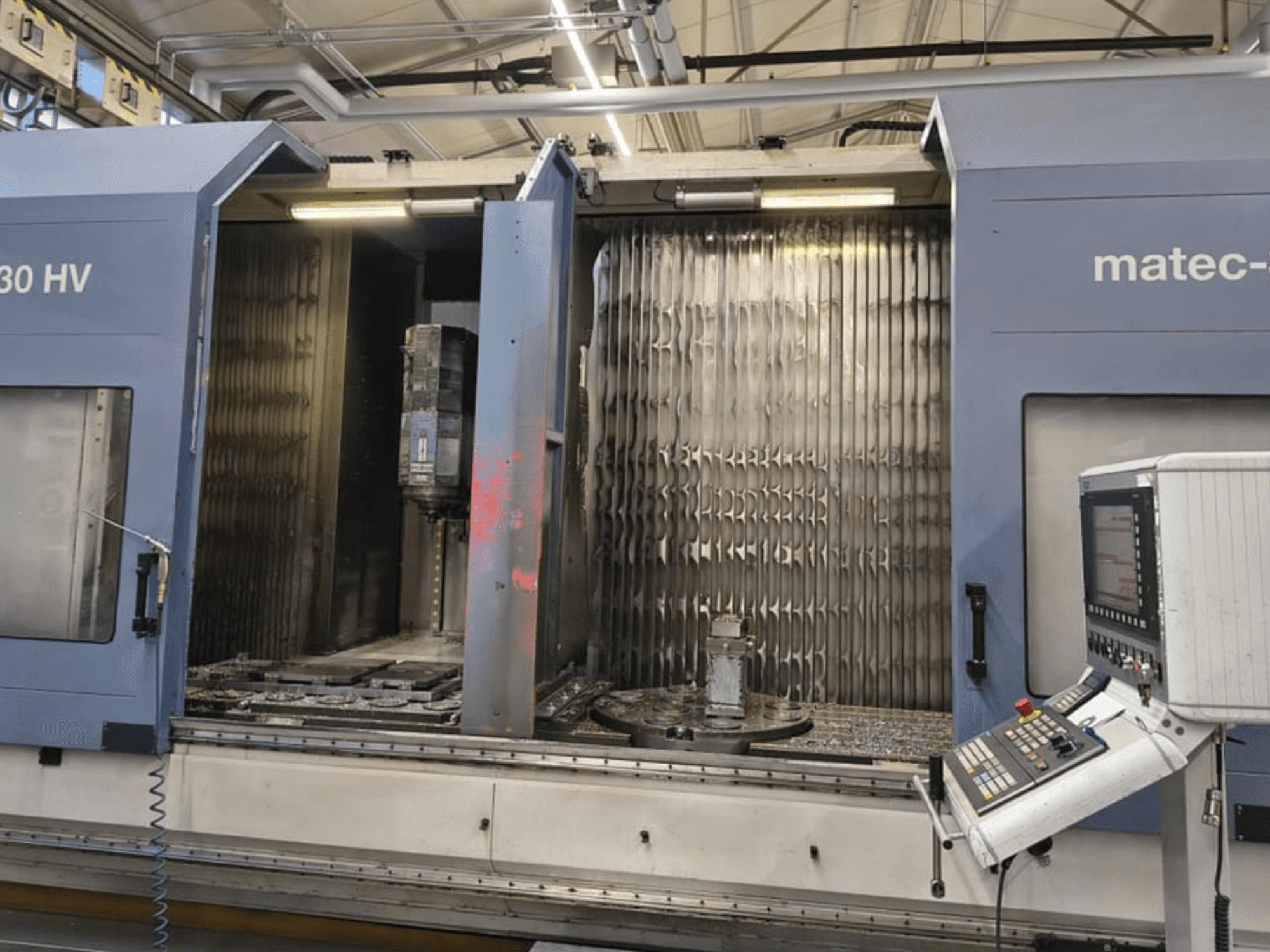 Vertical machining center Matec 30 HV with open doors, showing spindle, work table, and control panel from the front view.