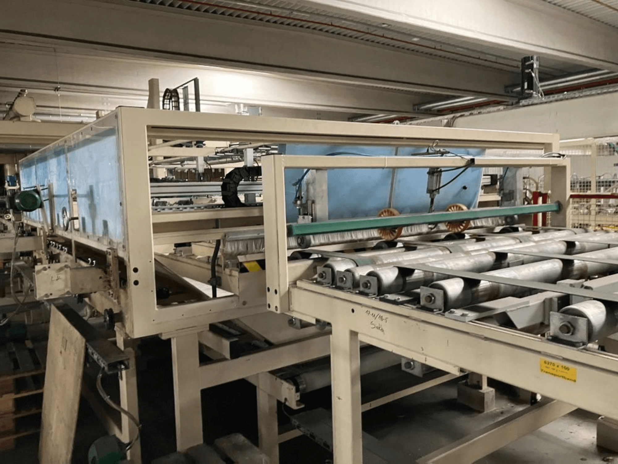 WEMHÖNER KT-F-1E laminating press, side view, featuring rollers and controls for material processing in a factory setting.