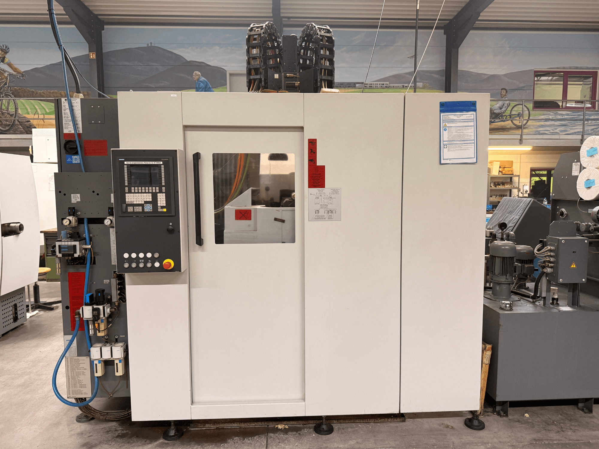 White CNC machining center with control panel, front view, featuring buttons and digital display, in a workshop setting.