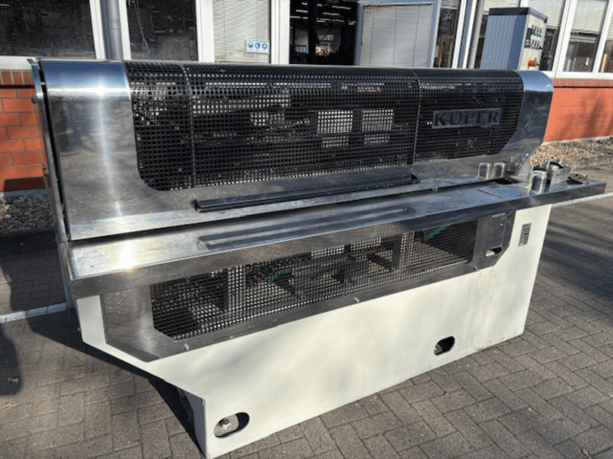 KUPER FLI veneer guillotine, front view, featuring a stainless steel body and protective mesh for safe operation.
