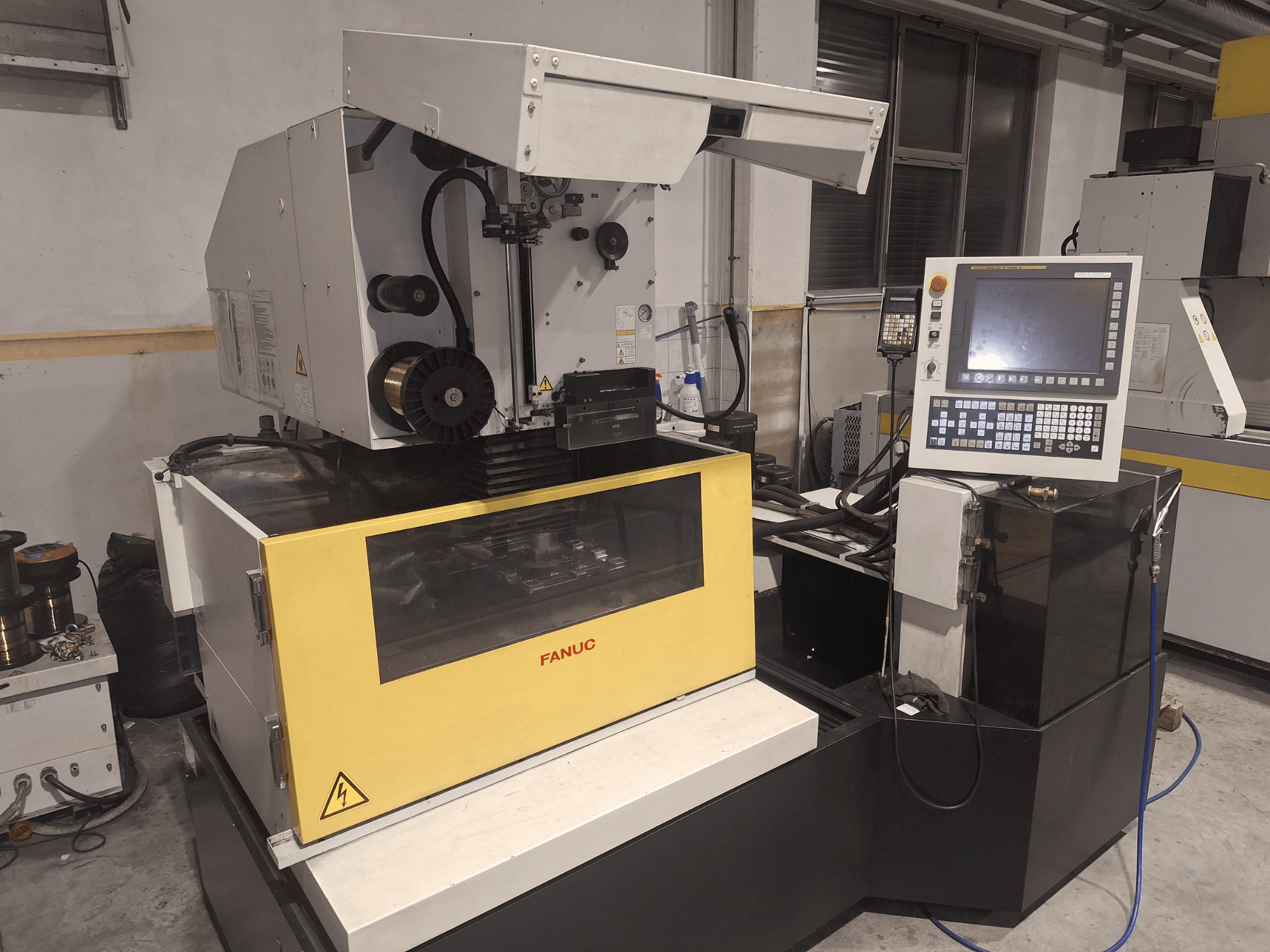 FANUC CNC machine in front view with open lid, revealing the work area and control panel on the right.