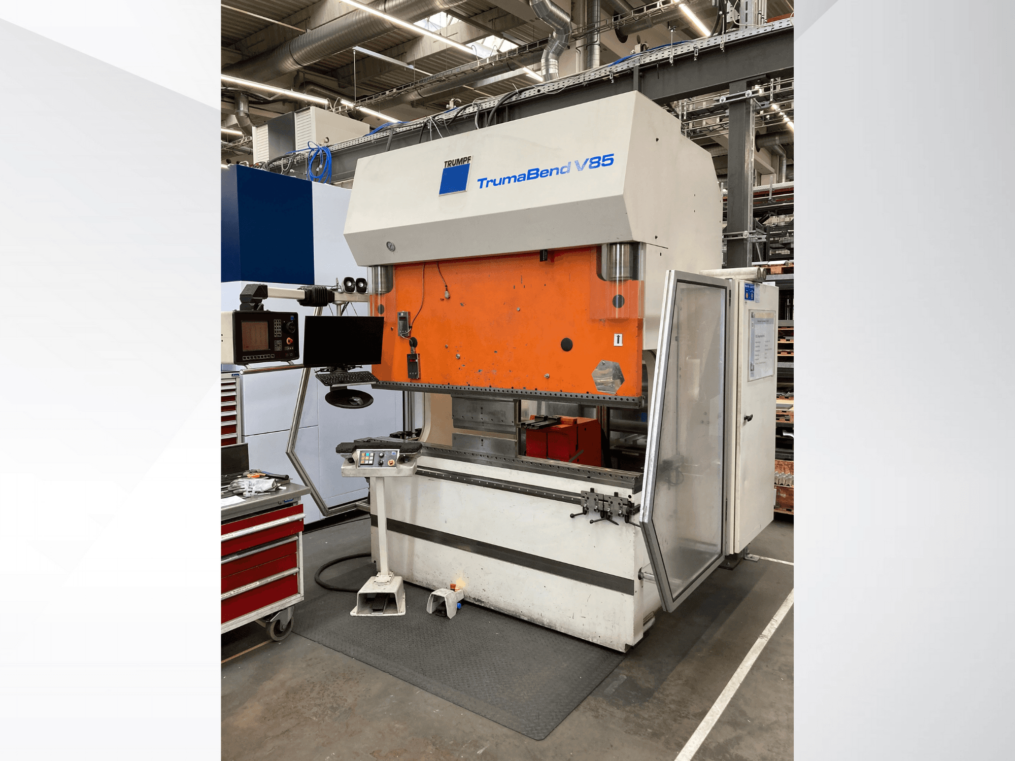 TruMatic V85 bending machine in a factory, featuring an orange front panel, control screen, and open side door, side view.